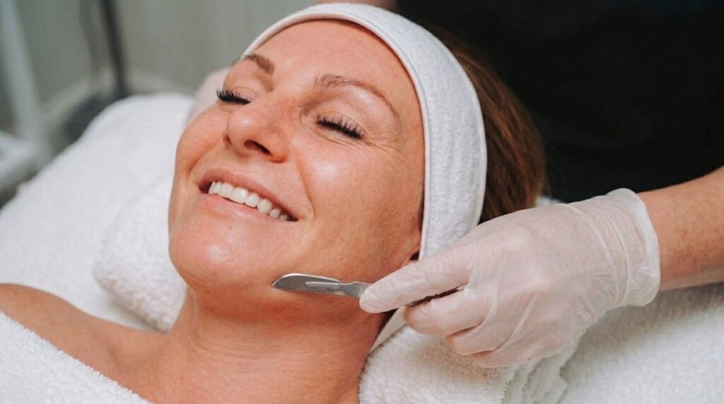 Schoonheidsspecialiste voert dermaplaning uit op de wang van een cliënte